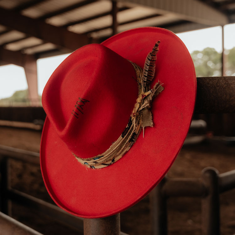 A red cowboy hat on a fence.